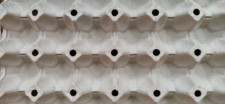 cardboard container for eggs close-up. Smooth rows, forms for laying eggs. Abstraction with convex and indented elements. Light and shadow. Rounded holes. Banner