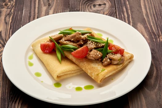 juicy pancakes with meat and tomatoes on a white plate. High quality photo