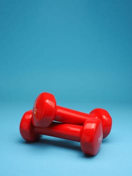 Red dumbbells on a blue background, space for your text, fitness or diet concept