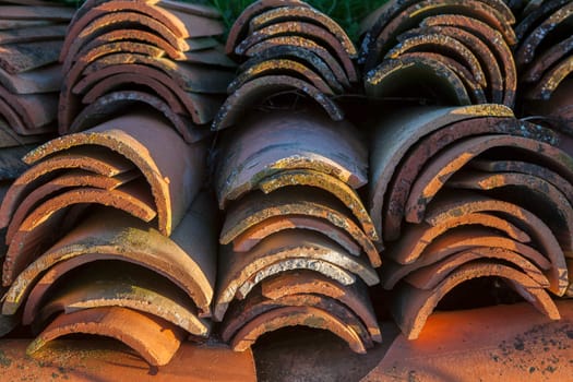 Piled of used mediterranean roof tiles with sunrise sun. Selective focus