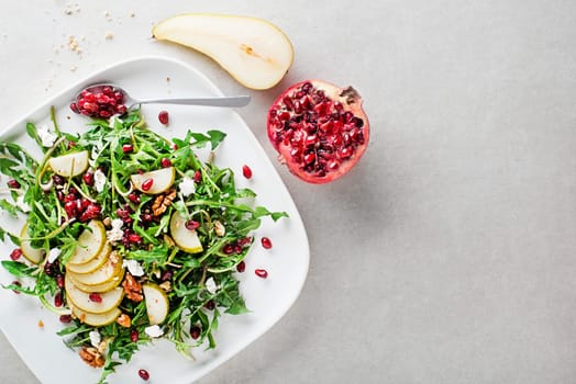 Healthy dandelion salad with pear fruit, pomegranate and fresh cheese close up