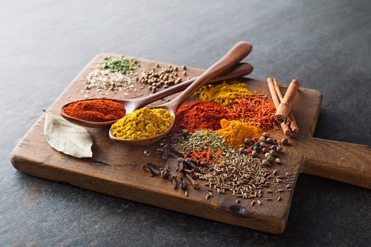 Colorful herbs and spices for cooking meal. Indian and asian spices On grey stone background.