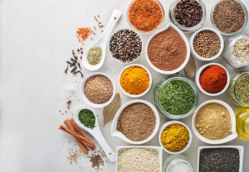 Colorful herbs and spices for cooking meal. Indian and asian spices On white stone background. Top view.