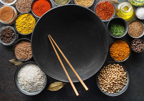 Colorful ingredients with herbs and spices for cooking meal. Asian spices for Chinese cuisine concept On dark wok background. Top view.
