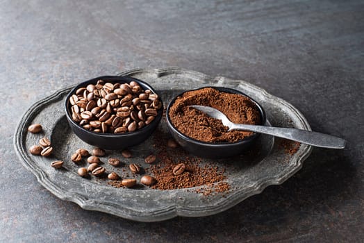 Coffee beans and freshly ground coffee powder on grey stone background close up