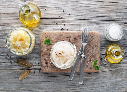Traditional fresh and healthy sauerkraut and sour turnip in glass jar on wooden background.