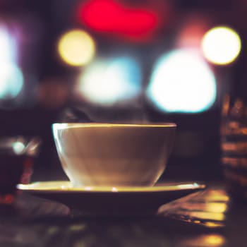 Cup of a hot tea in cafe. Anamorphic bokeh effect. Tilt-shift photo. Tasty aromatic tea in a lovely cup with a saucer. The tea is getting cold. Natural aroma. Label or advertisement. Evaporation