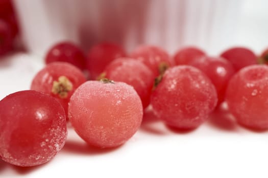Frozen currants lie in front of porcelain bowl
