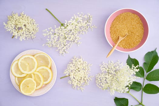 Elderflowers,sugar and lemons for making elderflower syrup on a table