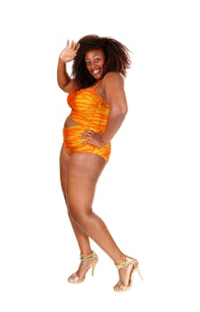 An African American young woman standing in profile in a orange bikini.on the floor, isolated for white background..