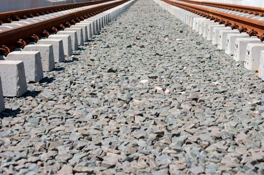The track bed of a newly laid rail line for a tram with rails,bases and gravel.