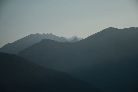 Mountains silhouette with peaks in the morning mist Saalfelden, Salzburg, Austria