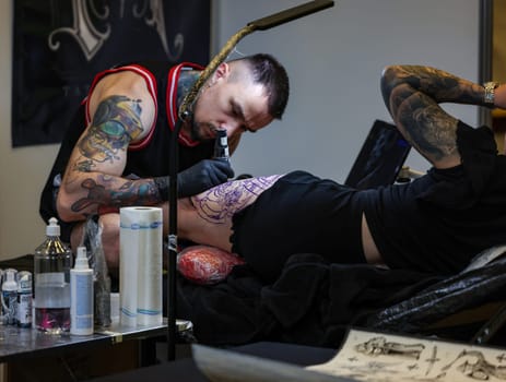 Krakow, Poland -  June 11, 2022: Unidentified  participant at 15th Tattoofest Convention in Cracow. One of the most prestigious tattoo festivals. Tattoo artist at work.