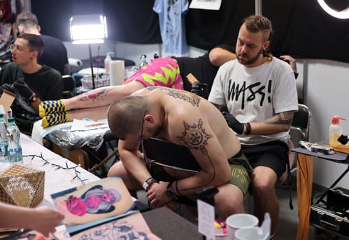 Krakow, Poland -  June 12, 2022: Unidentified  participant at 15th Tattoofest Convention in Cracow. One of the most prestigious tattoo festivals. Tattoo artist at work.