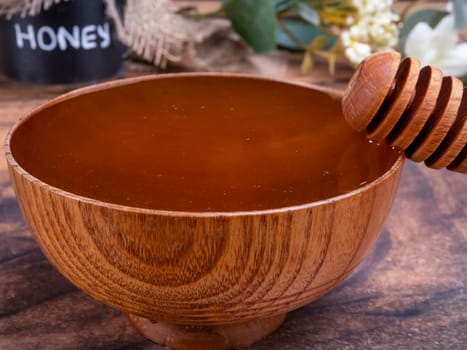 Honey spoon coming out of the bowl full of honey. Honey contains many nutrients, antioxidants, improves heart health, wound care, offers antidepressant and anti-anxiety benefits.
