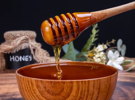 Honey spoon coming out of the jar full of honey. Honey contains many nutrients, antioxidants, improves heart health, wound care, offers antidepressant and anti-anxiety benefits
