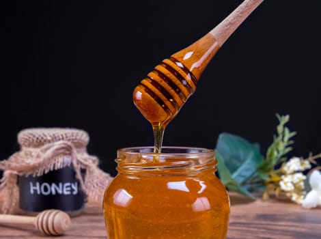 Honey spoon coming out of the jar full of honey in slow motion. Honey contains many nutrients, antioxidants, improves heart health, wound care, offers antidepressant and anti-anxiety benefits.