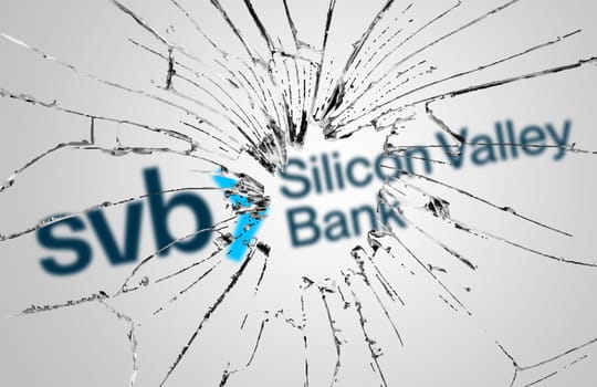 Santa Clara, USA, March 2023: Broken glass with the Silicon Valley Bank logo blurred in the background. Bank run and bankruptcy. Finance and economy. Illustrative editorial
