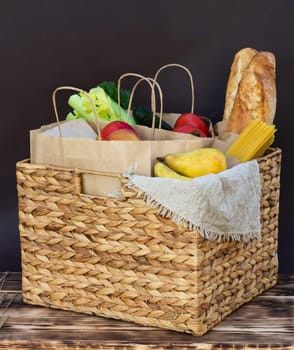 Fresh eco organic vegetables, greens and fruits, cereals and pasta in a wicker basket. Delivery or donation of ecological farm food concept