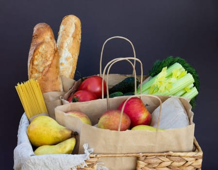 Fresh eco organic vegetables, greens and fruits, cereals and pasta in a wicker basket. Delivery or donation of ecological farm food concept