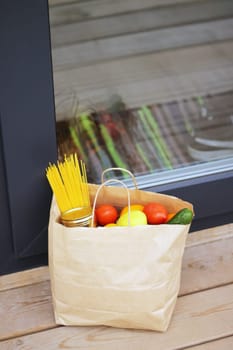 Quarantine contactless delivery, paper bag near the door. House entrance with delivered bag. Prevention measures of coronavirus, vertical