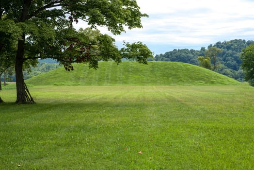 Magnificent grass covered indigenous prehistoric burial mound built by people of the Hopewell Culture in present day Ohio. No people, sunny outdoors, with copy space