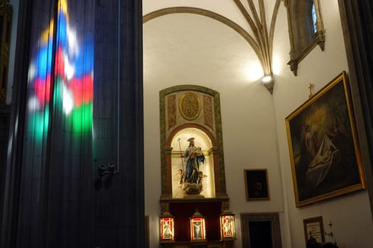 Innenansicht der Santa Ana Kathedrale - Buntglasfenster werfen Farben auf einen Pfeiler an einem Seitenaltar, Gran Canaria, Spanien, Las Palmas