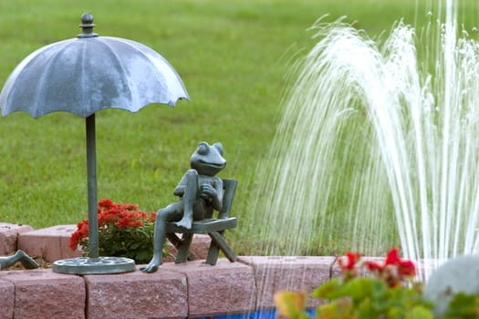 A Statue of a frog next to a fountain.