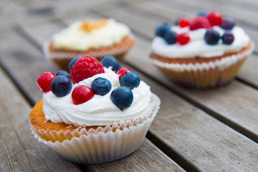 muffins on wooden ground with blueberry, raspberry and whipping cream