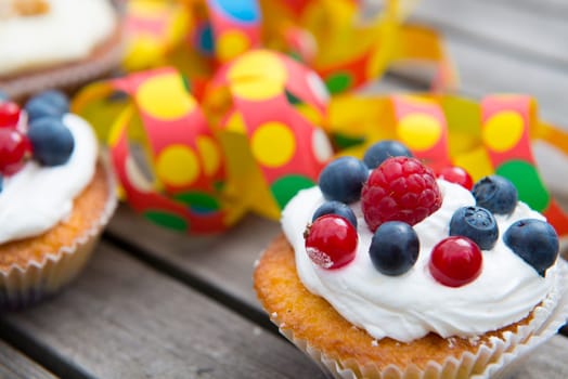 muffins on wooden ground with blueberry, raspberry and whipping cream