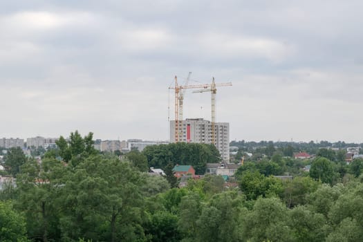 Three high tower crane building a new house flats in a beautiful green park area of the city.