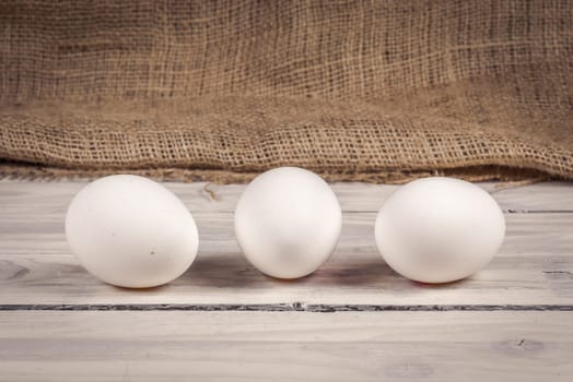Three white eggs on a old wooden table