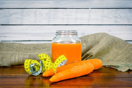 Carrots and juice with measure tape on a wooden table