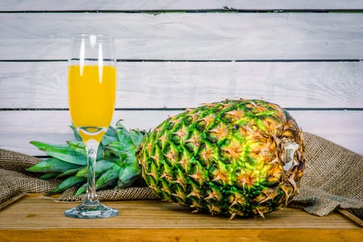 Pineapple fruit and juice on a wooden table