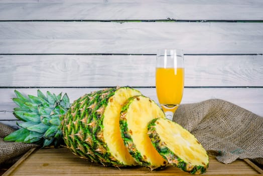 Pineapple fruit and juice on a wooden board