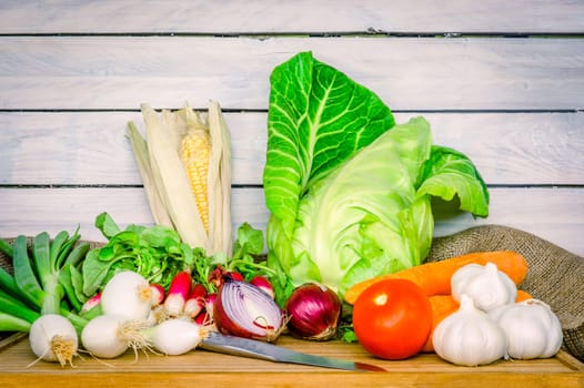 Mix of vegetables on a wooden table with a knife