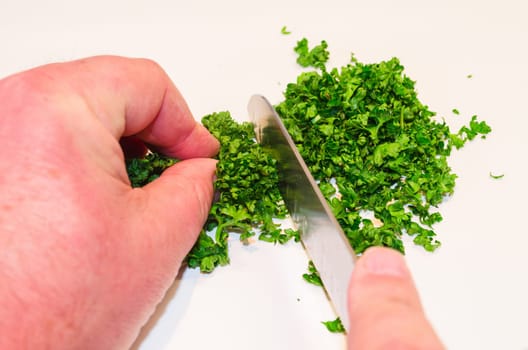 Chopping parsley with a knife on a cutting board...