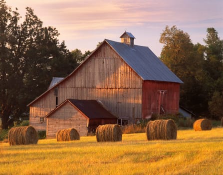 A barn in N. Hero, Vermont with round bales of hay.