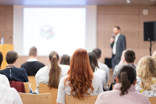 Speaker giving a talk in conference hall at business event. Rear view of unrecognizable people in audience at the conference hall. Business and entrepreneurship concept