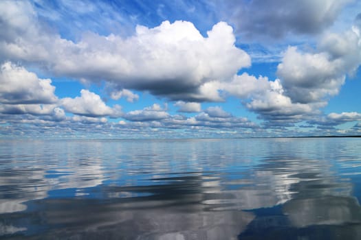 beautiful seascape, cumulus clouds in the blue sky are reflected in the smooth water