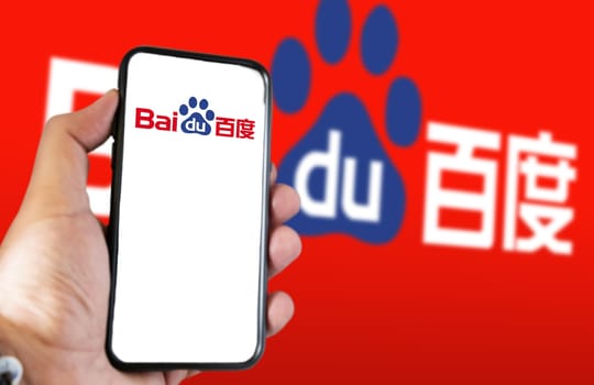 Beijing, CN, Feb 2023: A hand holding a phone with the Baidu website on the screen. Red background with blurred Baidu logo. Baidu is a Chinese multinational technology company