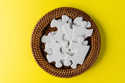 White jigsaw puzzle in container under yellow background