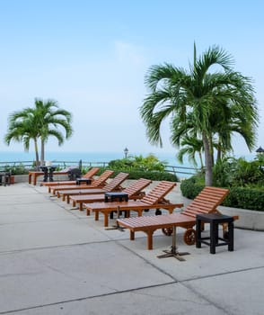 Wooden beach chairs at swimming pool with sea background