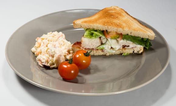 Club Sandwich on Plate with Coleslaw and tomatoes.