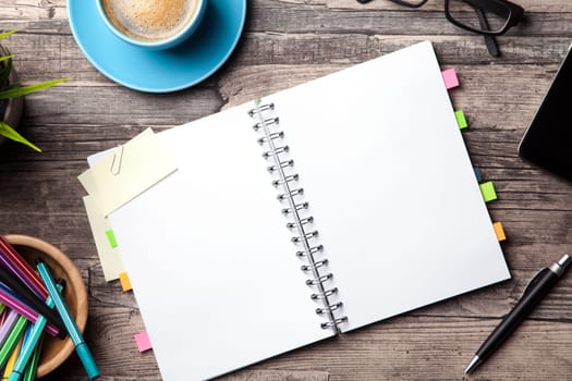 Office table with a coffee cup, a blank notepad and a plant