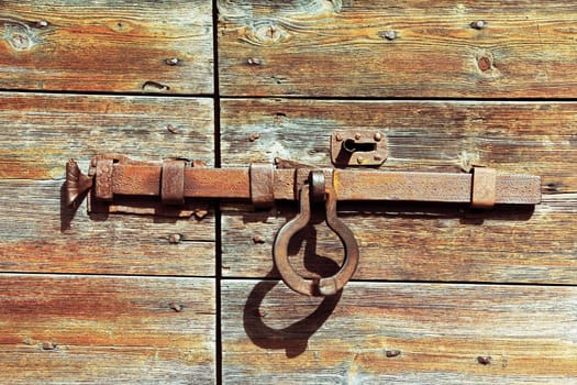 The metal lock on an old wooden door. Closed door