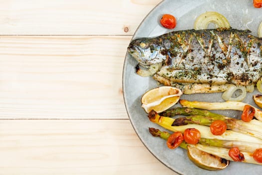 Delicious trout fish baked with white asparagus on wooden table