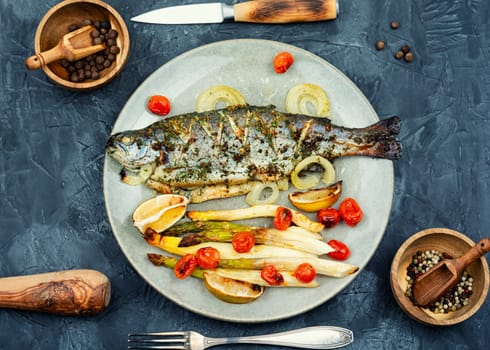 Delicious trout fish baked with white asparagus on wooden table