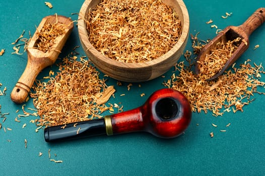 Fragrant smoking tobacco and a smoking tube or pipe on the table.