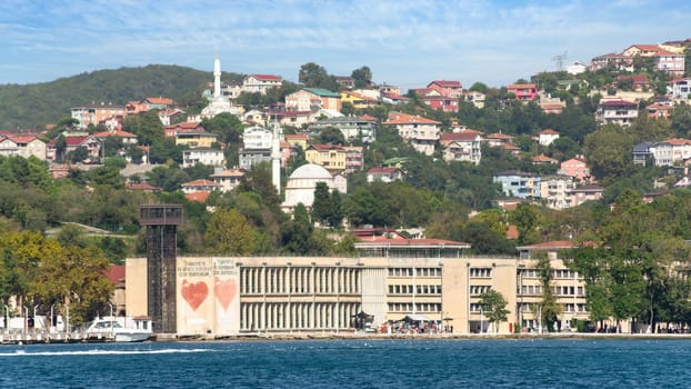 Istanbul, Turkey - August 29, 2022: View from Bosphorus strait of the green mountains of the Asian side, with traditional old buildings and dense trees in a summer day